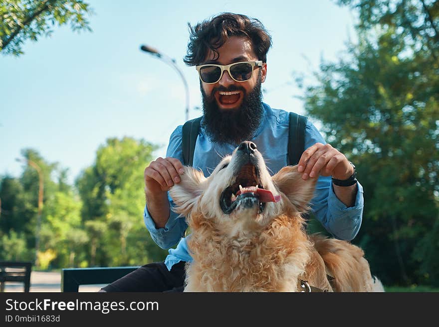 Man and dog having fun, playing, making funny faces while resting in the park. Life is beautiful, best friends concept.