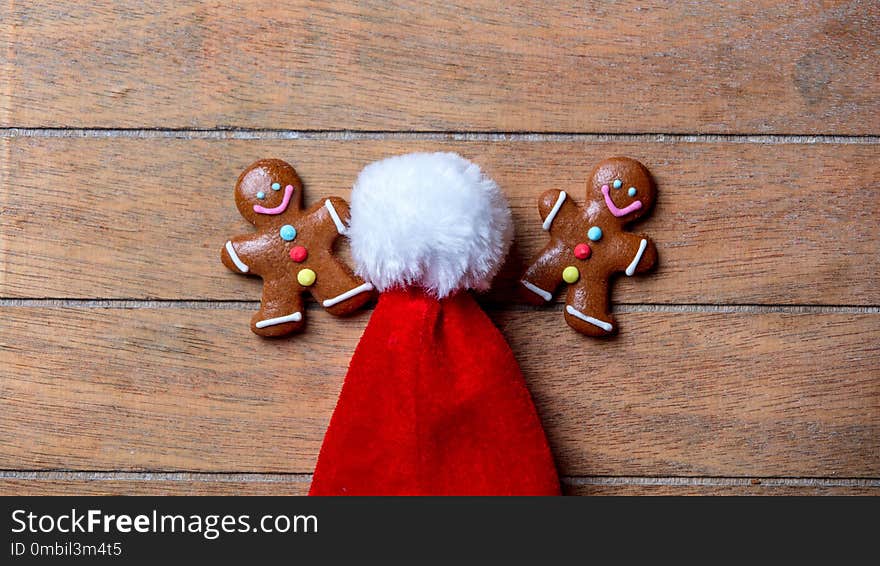 Gingerbread cookie and Santa Claus hat on wooden table