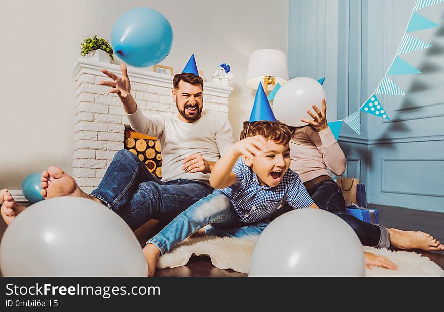 Party in progress. Optimistic enthusiastic family laughing while playing on floor. Party in progress. Optimistic enthusiastic family laughing while playing on floor