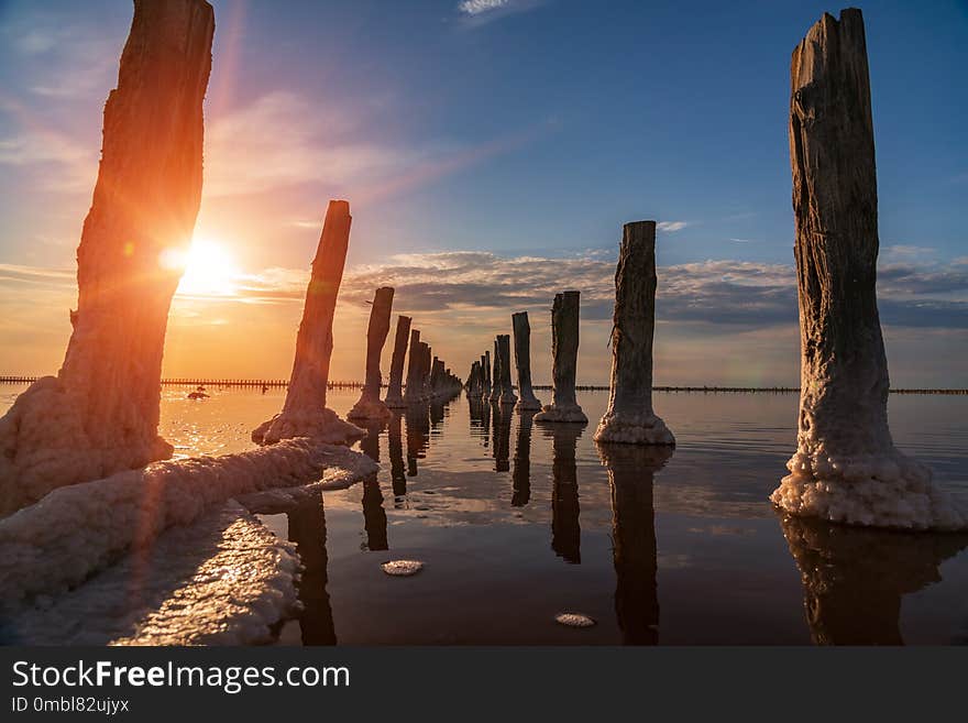 Sunset on a pink salt lake, a former mine for the extraction of pink salt. row of wooden pegs overgrown with salt.