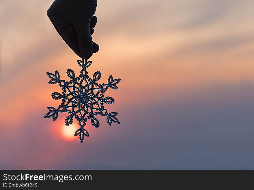 Sparkling huge snowflake on a sunset sky background. Winter and Christmas concept.