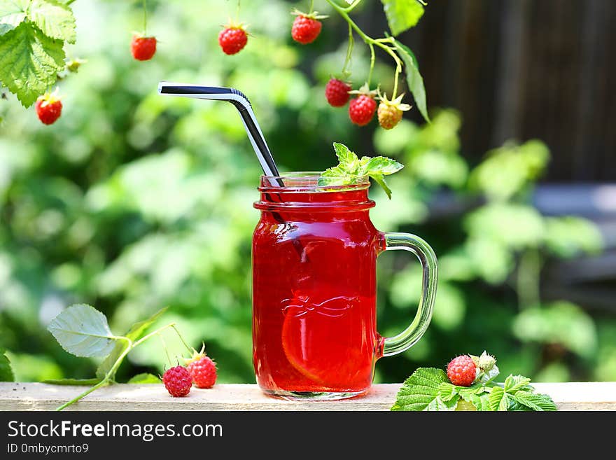 Raspberry jam and fresh raspberry on a rustic wooden table outdoors. Authentic lifestyle image. Seasonal harvest crop local produce concept. Raspberry jam and fresh raspberry on a rustic wooden table outdoors. Authentic lifestyle image. Seasonal harvest crop local produce concept.