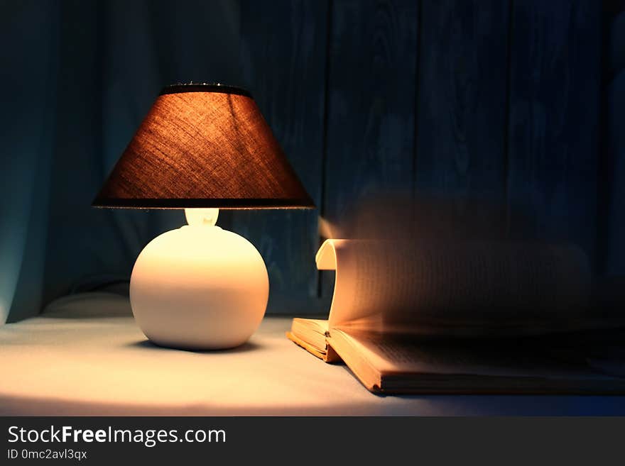 Still-life lamp with a book on a table on a blue background