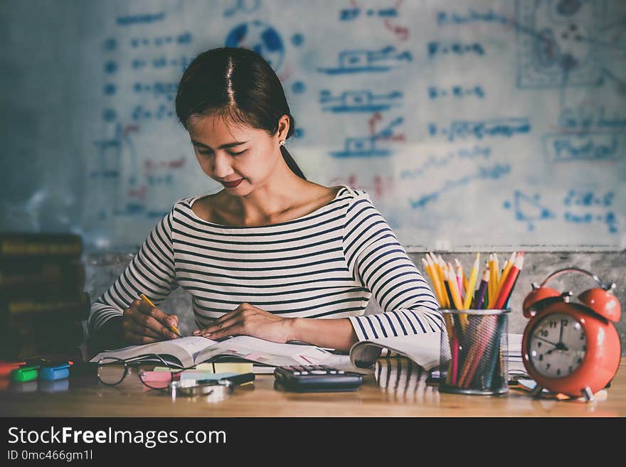 Young student sitting at desk in home studying and reading, doing homework and lesson practice preparing exam to