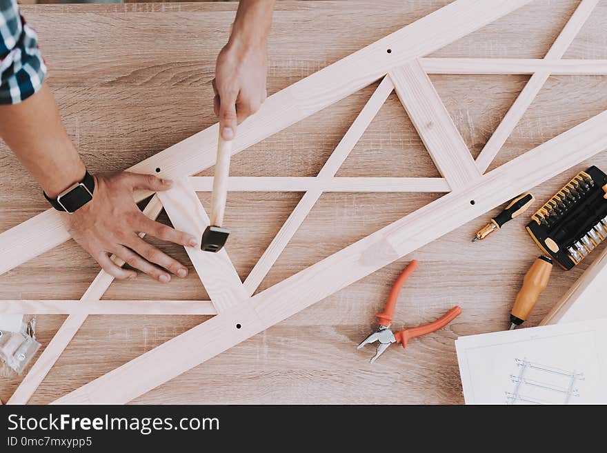 Young Man Assembling Wooden Bookshelf at Home. Wooden Bookcase. Selfmade Furniture. Man and Hobby. White Room. Engineer with Tool. Young Man at Home. Homemade Decoration. Modern Furniture.