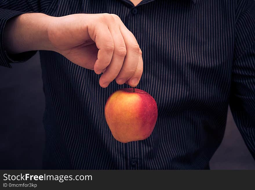 A man holding a red apple in hand. A man holding a red apple in hand