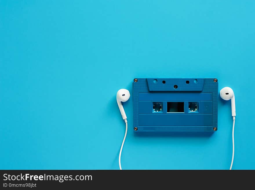 Retro cassette tape with earphones on blue background for music and relaxation concept