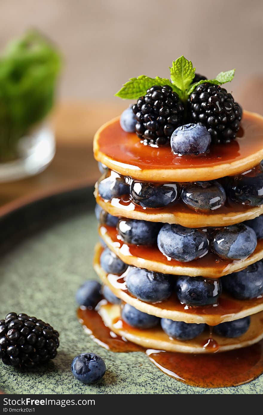 Tasty pancakes with berries and syrup on plate