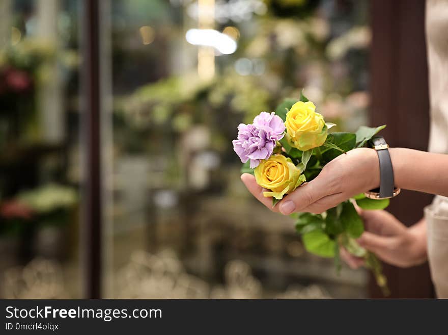 Female florist holding beautiful bouquet in flower shop, closeup