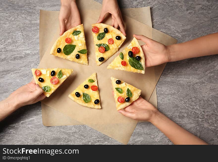 People taking tasty homemade pizza slices from table, top view