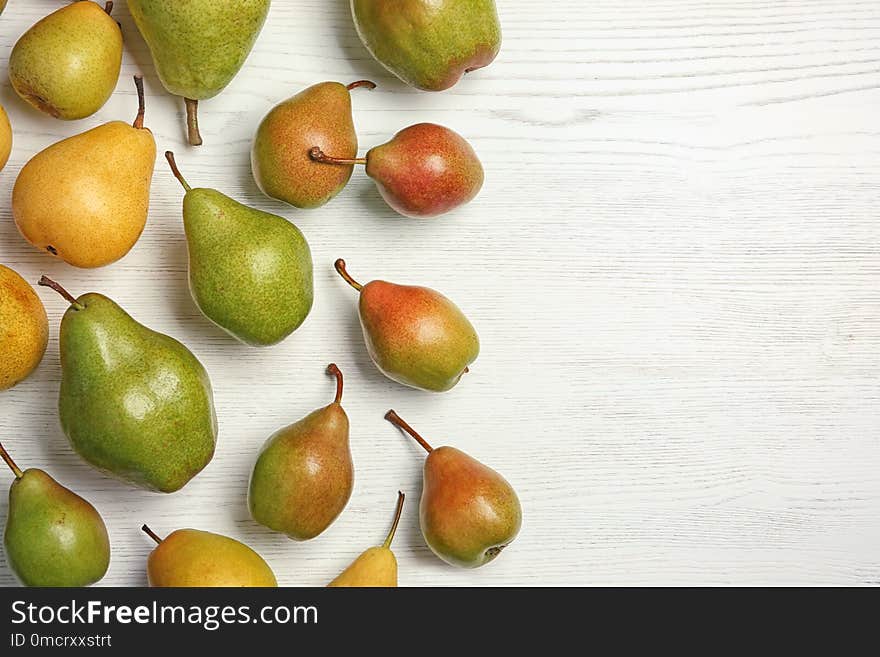 Ripe pears on white wooden background, top view. Space for text