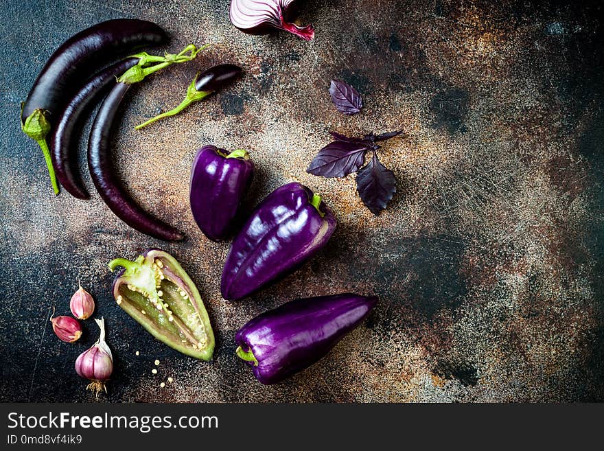 Raw purple seasonal vegetables over rustic background. Top view, flat lay, copy space. Raw purple seasonal vegetables over rustic background. Top view, flat lay, copy space