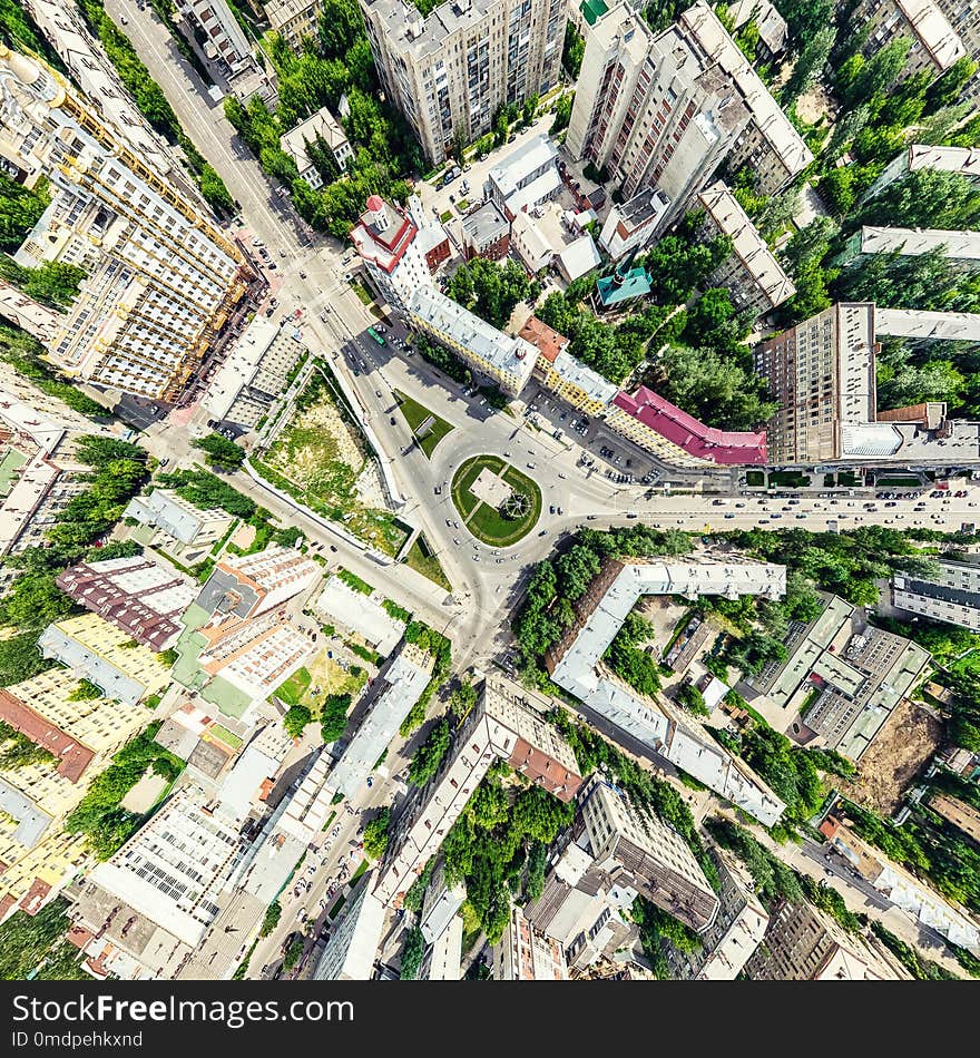 Aerial city view with crossroads and roads, houses, buildings, parks and parking lots. Sunny summer panoramic image