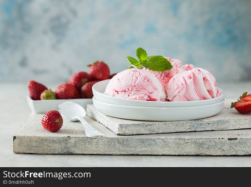 Scoops of delicious ice-cream and strawberry on white background. Scoops of delicious ice-cream and strawberry on white concrete background. Scoops of delicious ice-cream and strawberry on white background. Scoops of delicious ice-cream and strawberry on white concrete background