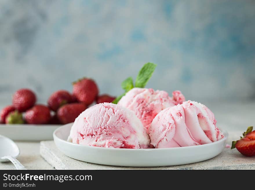 Scoops of delicious ice-cream and strawberry on white background. Scoops of delicious ice-cream and strawberry on white concrete background. Scoops of delicious ice-cream and strawberry on white background. Scoops of delicious ice-cream and strawberry on white concrete background