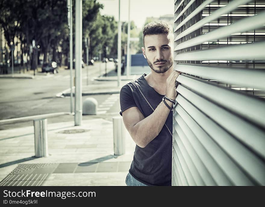 One handsome young man in urban setting in European city, wearing jeans and black t-shirt. One handsome young man in urban setting in European city, wearing jeans and black t-shirt