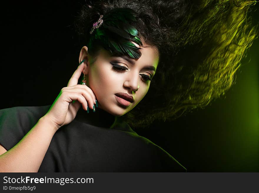 Pretty and young brunette with long curly hair on a dark background. Pretty and young brunette with long curly hair on a dark background