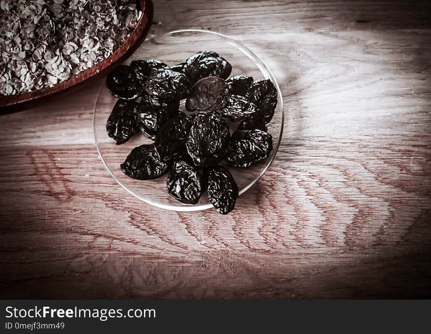 Prunes in a bowl and cereal on a wooden table