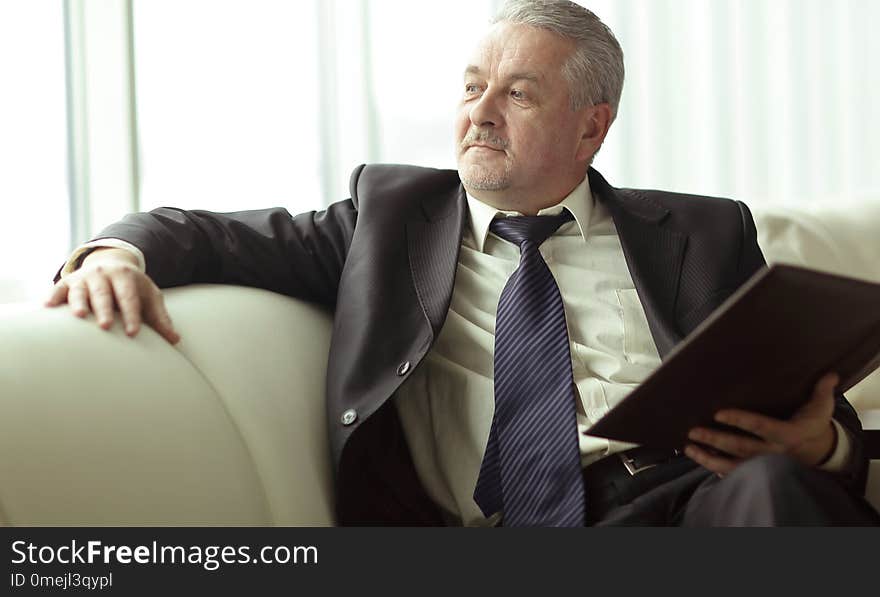 Boss with clipboard sitting on the office couch.business concept