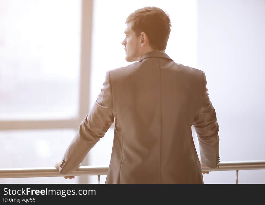 Rear view. businessman in casual wear standing and thinking near the office window.