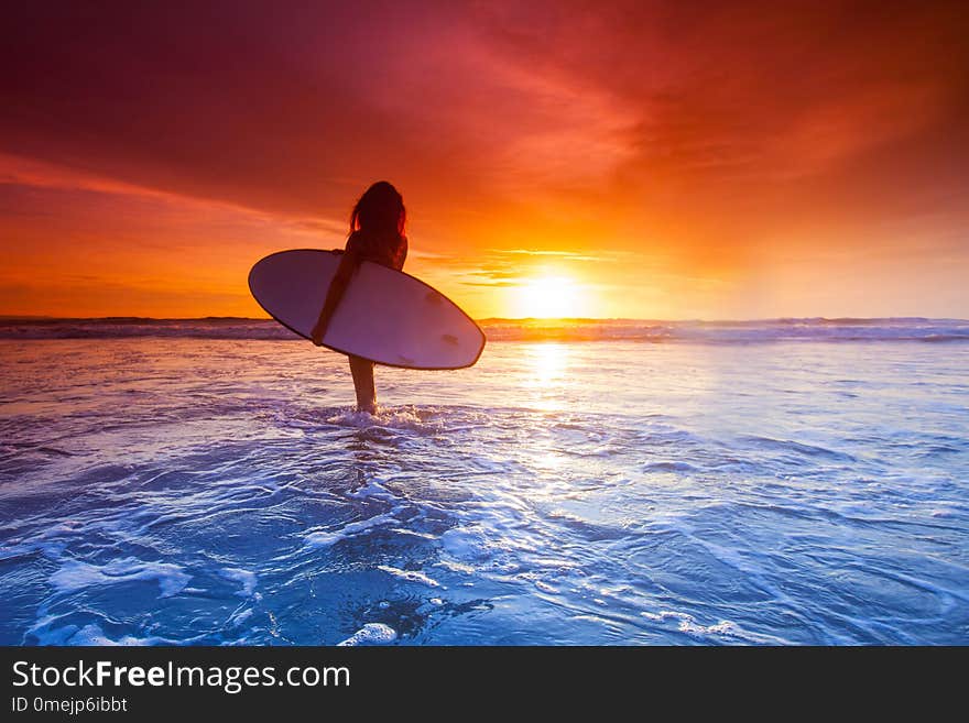 Surfer woman on beach at sunset