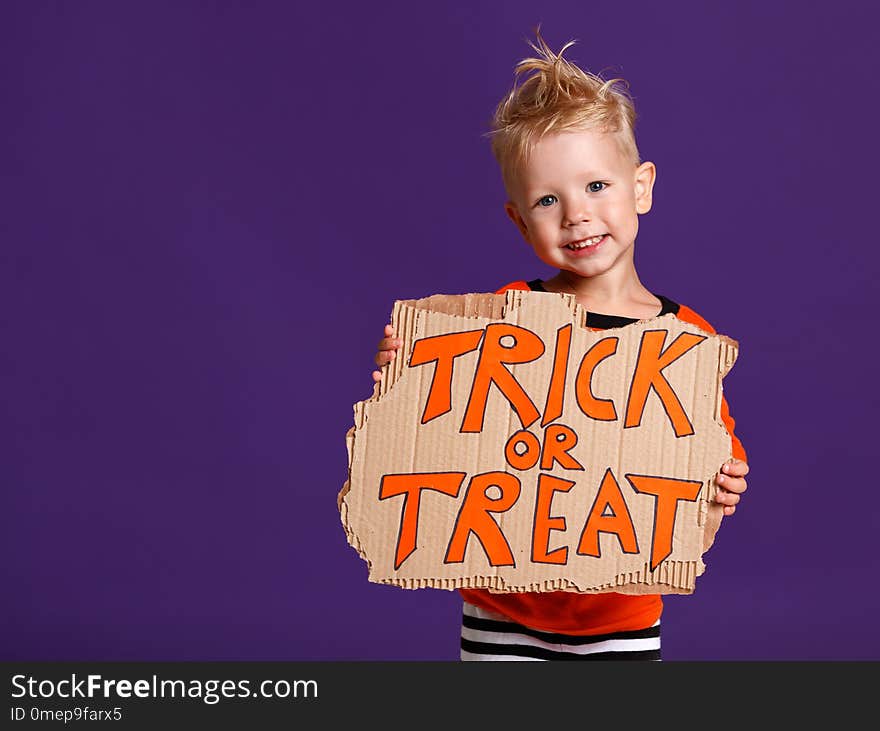 Happy Halloween! cheerful child boy in costume with pumpkins on a violet purple background