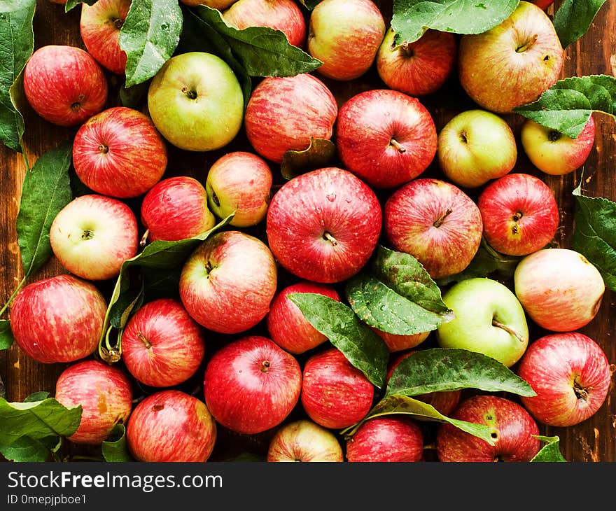 Ripe red apples with leaves on wooden background. Shallow dof. Ripe red apples with leaves on wooden background. Shallow dof.