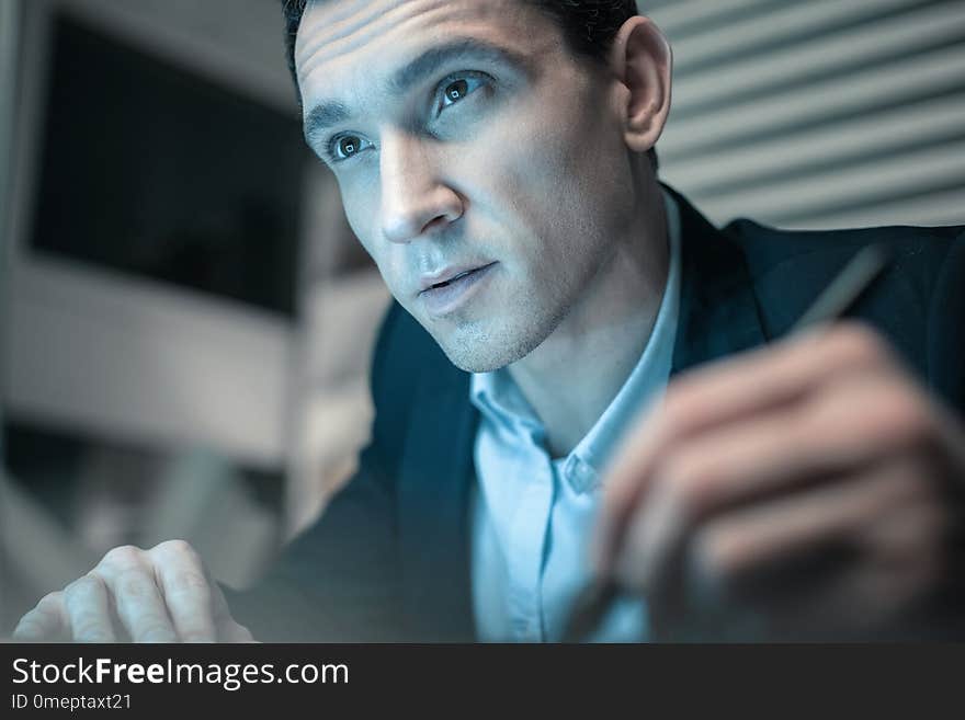 Important information. Portrait of young concentrated man making notes holding a pencil