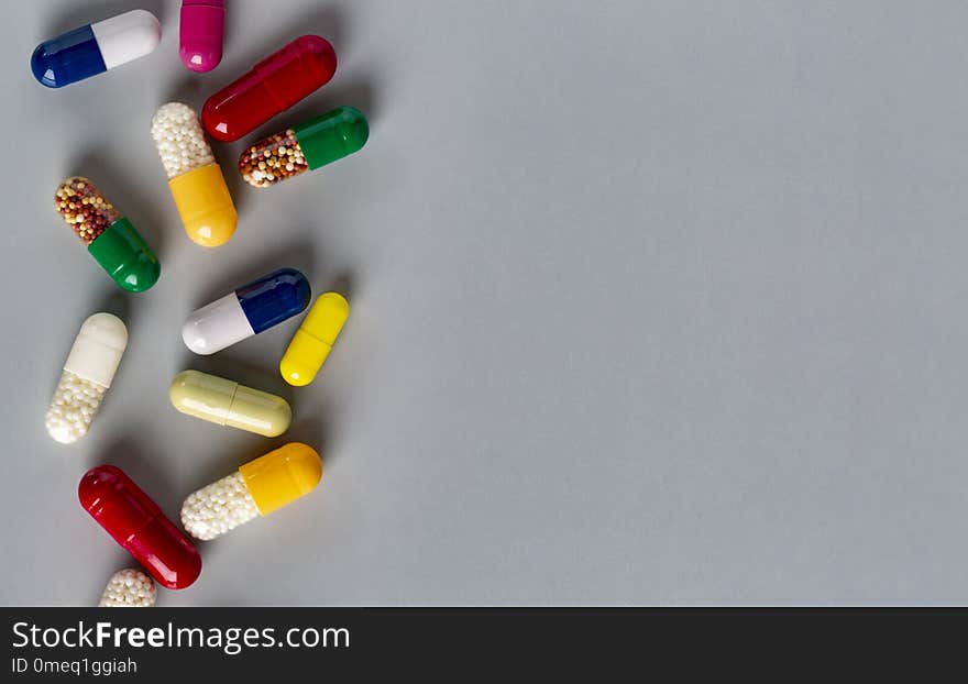 Closeup different medicine capsules and pills on grey background. Closeup different medicine capsules and pills on grey background