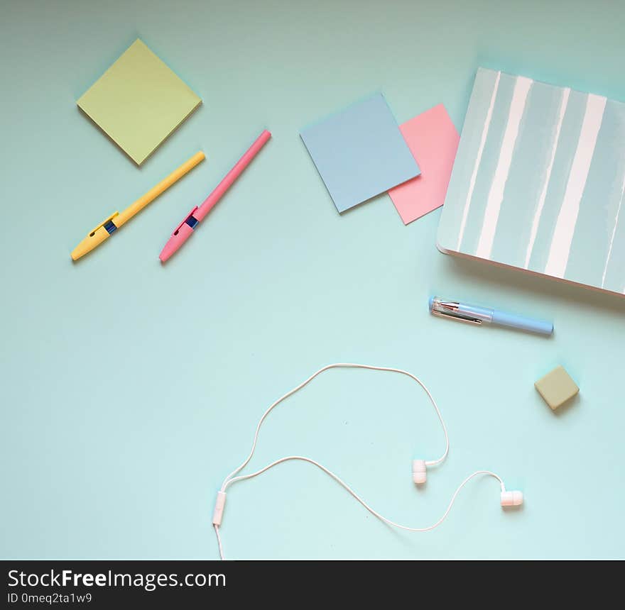 Pen, stickers, headphones and Notepad lie on a blue background. Pen, stickers, headphones and Notepad lie on a blue background.