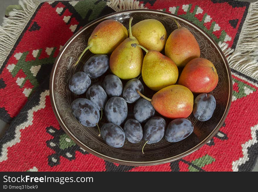 Still life with plums and pears on a red background