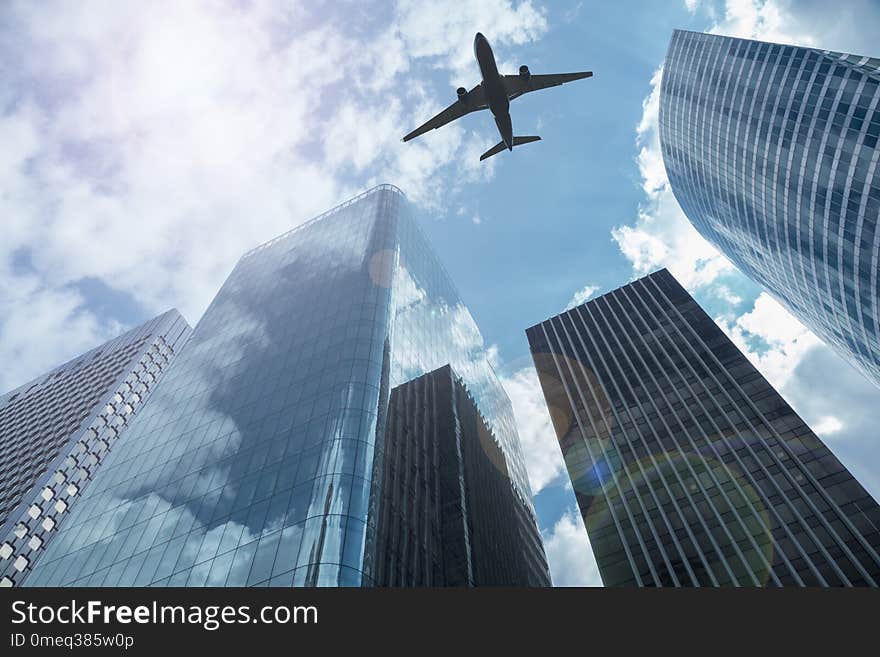 Airplane in the sky with modern buildings, with a blue sky