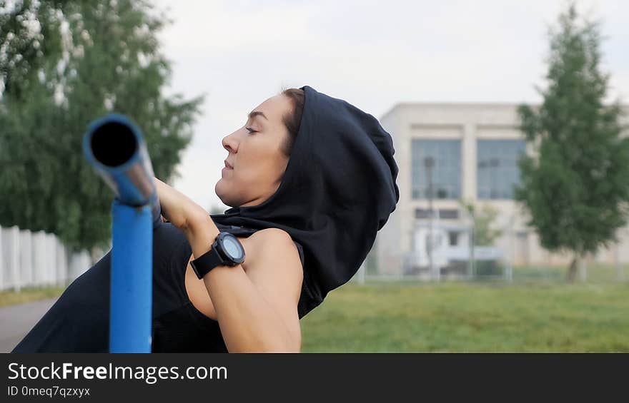 Fitness woman workout doing exercises on a horizontal bar outdoors, copyspace