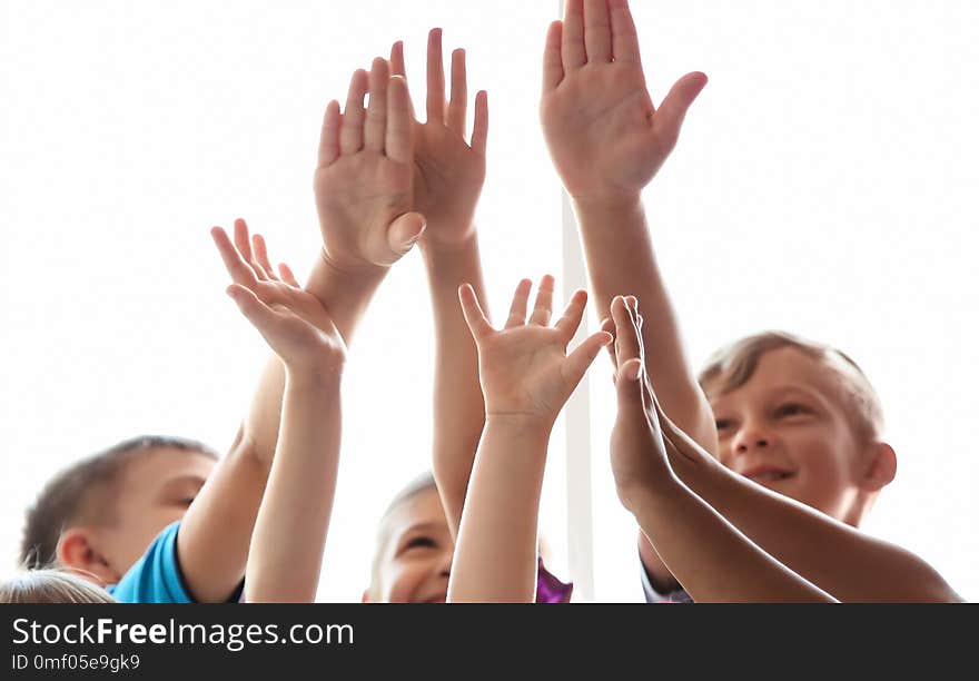 Little children raising hands together on light background. Unity concept