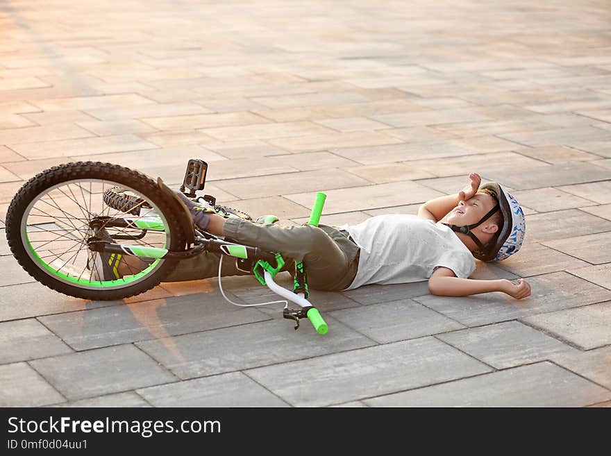 Little boy fallen off his bicycle on street