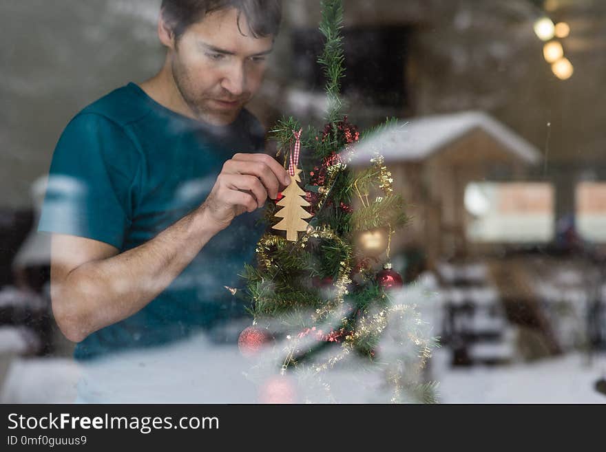 Young man hanging wooden tree on a Christmas tree