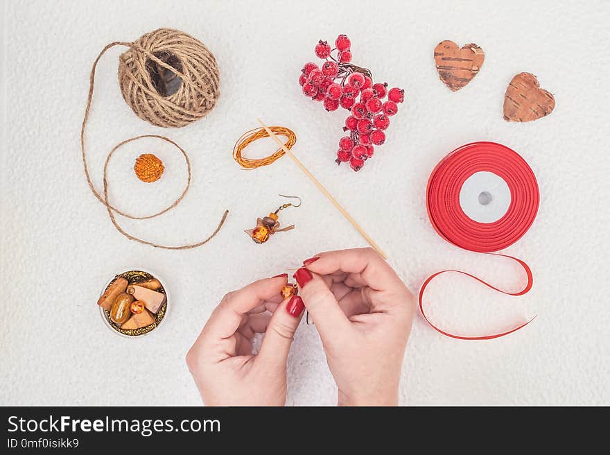 Handmade Jewelry, DIY flat lay in red and brown. Jewelry designer workplace. Woman hands making handmade earrings with amber. Freelance fashion femininity workspace in flat lay style.