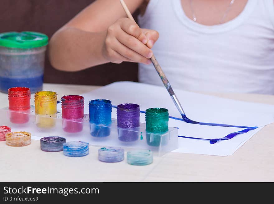 Hands of painting boy using gouache on white paper