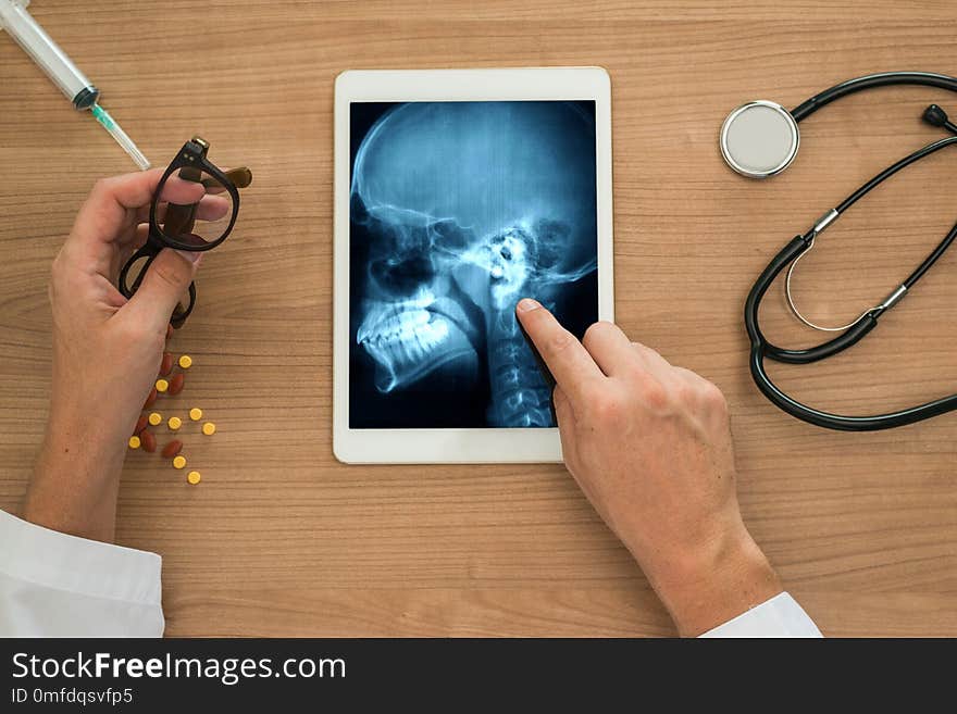 Hand of a doctor showing a xray of ears and skull on a digital tablet