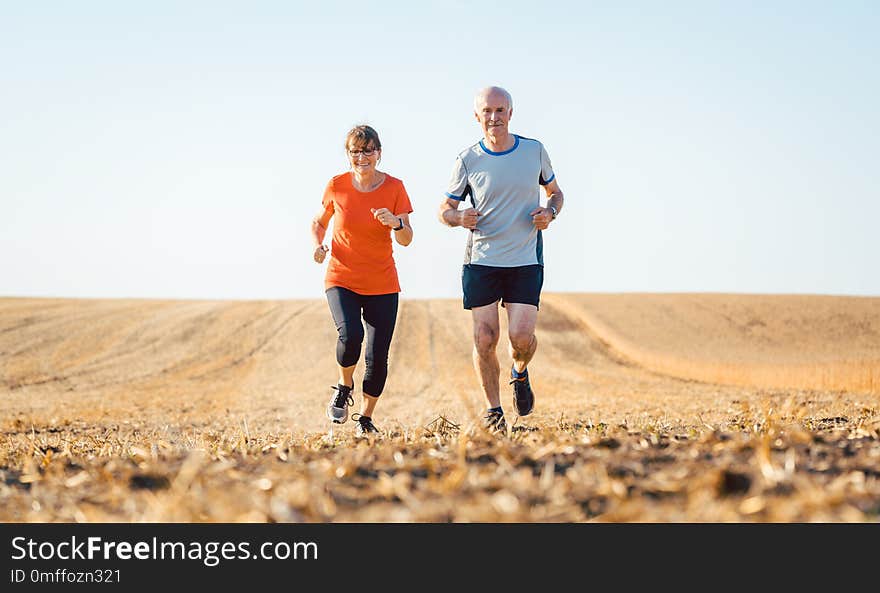 Senior women and men running or jogging on a field to remain fit and healthy. Senior women and men running or jogging on a field to remain fit and healthy