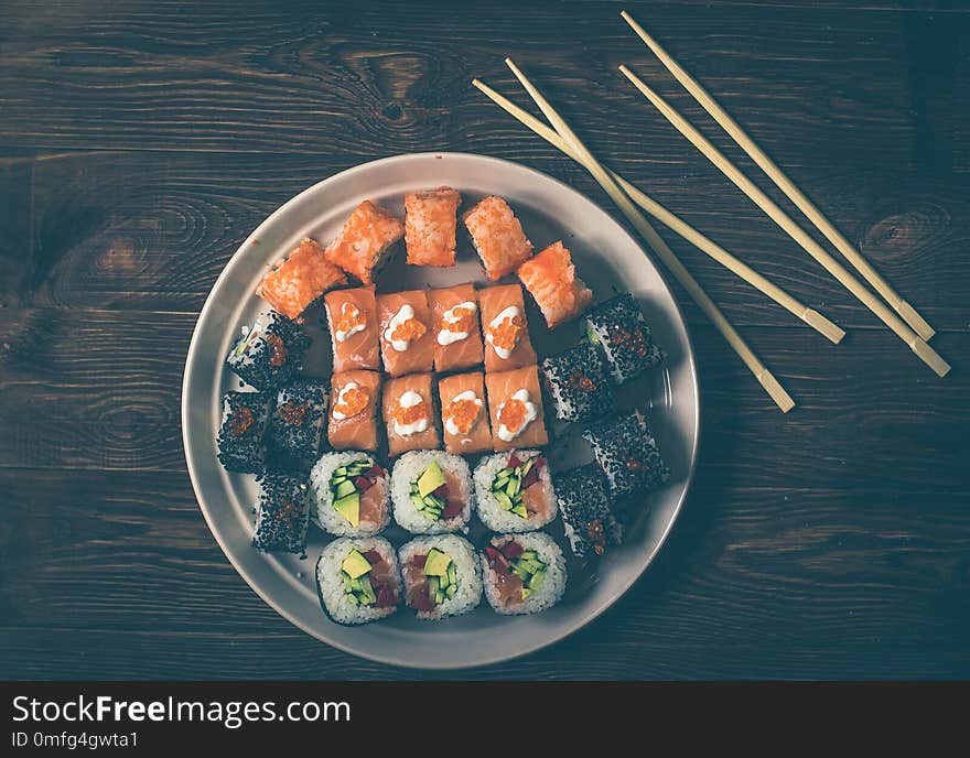 Different Sushi rolls,wasabi and ginger on a plate on wooden background