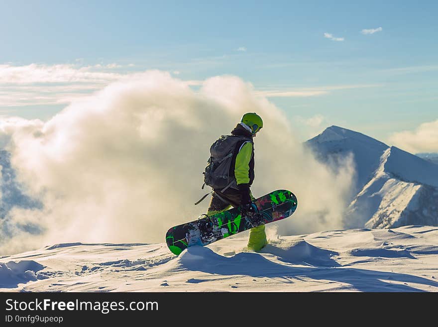 Snowboarder freerider is standing in the snowy mountains in winter under the clouds