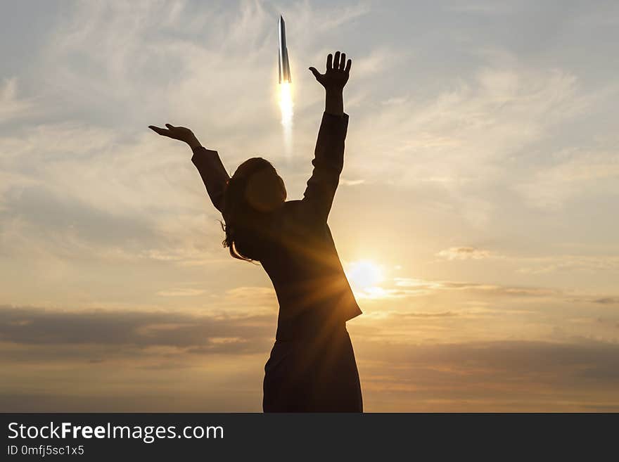 Businesswoman raised his hands on the background of the rocket taking off .Concept of start up successful.