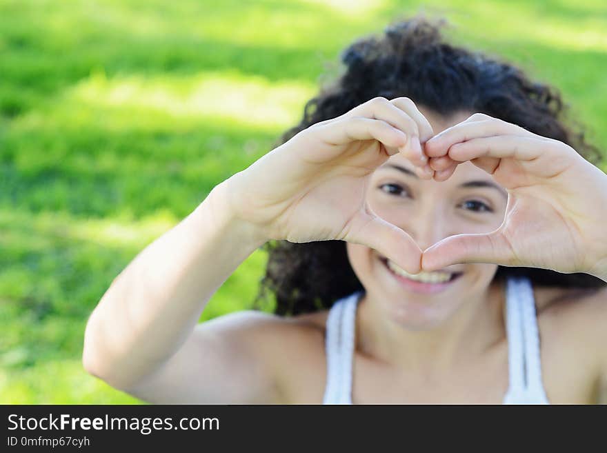 Close up focus woman hands show love symbol on green nature outdoor park. Young latin girl. Close up focus woman hands show love symbol on green nature outdoor park. Young latin girl.