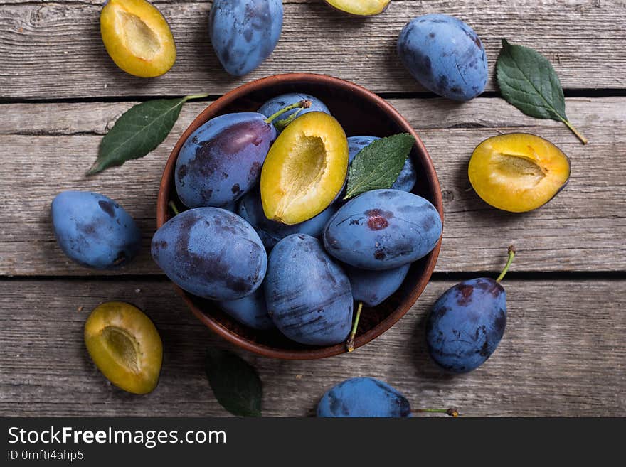 Fresh plums in bowl on wooden table . Fruit background