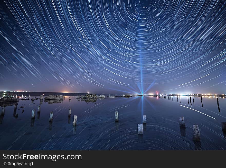 Lake at night with amazing starry sky and star tracks with reflections in the water. Natural outdors travel background.