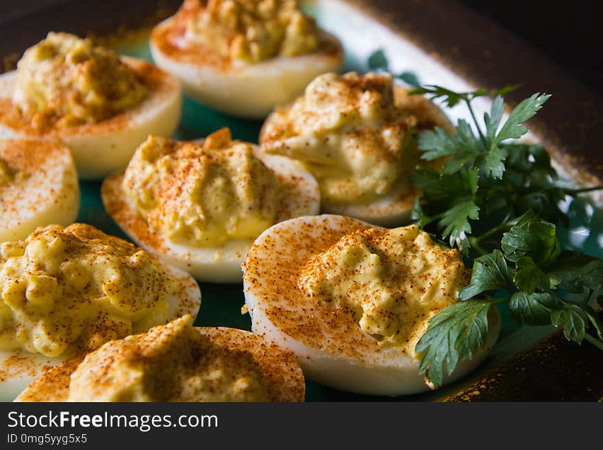 Deviled eggs on a plate with paprika and parley to the side. Deviled eggs on a plate with paprika and parley to the side