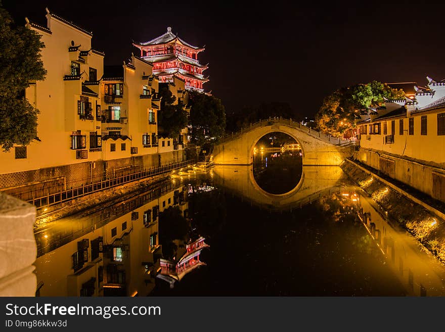 Historic China waterway night scene near Hefei China there is a railed walkway along the side of the waters edge. City lights reflect in the water and one old Chinese building stands out in the background with the blck night sky. Historic China waterway night scene near Hefei China there is a railed walkway along the side of the waters edge. City lights reflect in the water and one old Chinese building stands out in the background with the blck night sky.