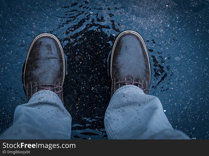 Shoes of male adult in puddle on the streets while its raining cats and dogs. Shoes of male adult in puddle on the streets while its raining cats and dogs