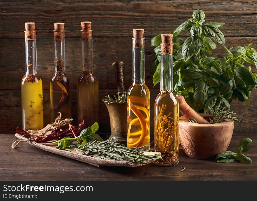 Olive oil with different spices and herbs on a old wooden table. Olive oil with different spices and herbs on a old wooden table.